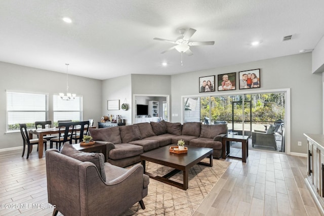 living room with ceiling fan with notable chandelier and a textured ceiling