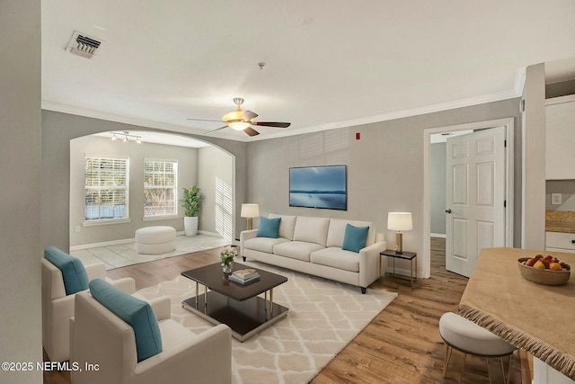 living room with light hardwood / wood-style flooring, crown molding, and ceiling fan with notable chandelier