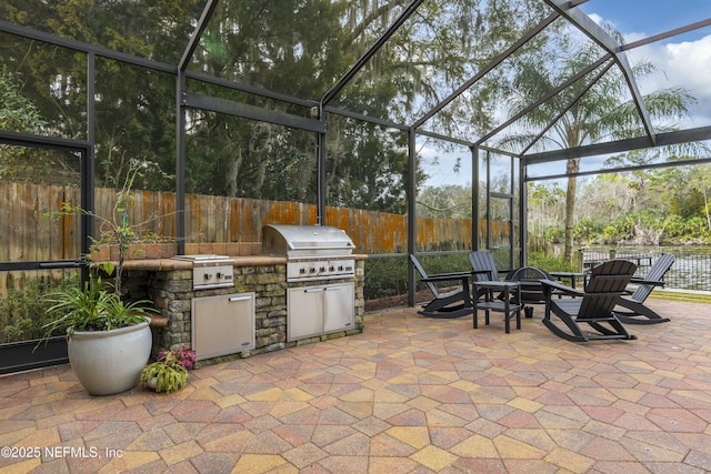 view of patio with exterior kitchen, a lanai, and grilling area