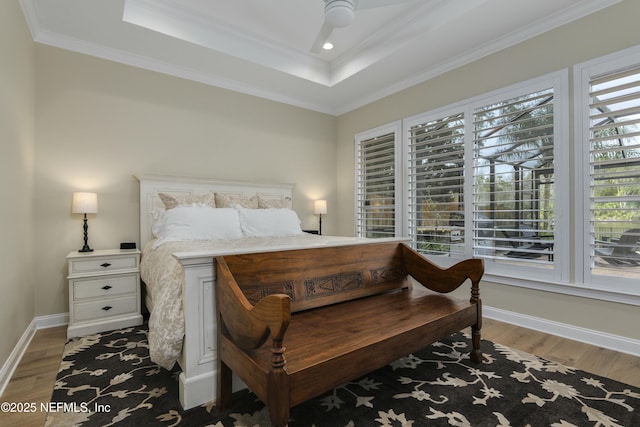 bedroom featuring ornamental molding, ceiling fan, a tray ceiling, and dark hardwood / wood-style flooring