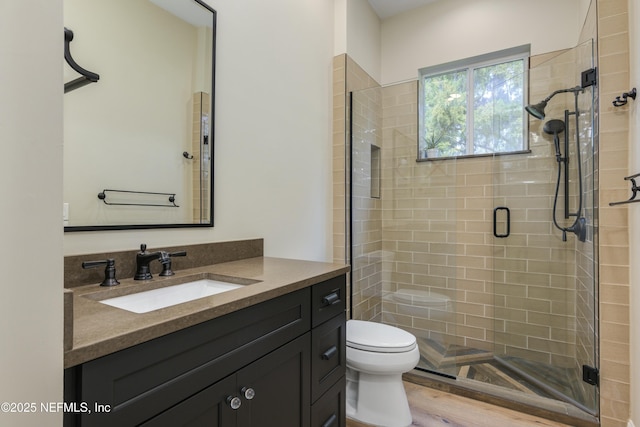 bathroom featuring a shower with door, hardwood / wood-style flooring, vanity, and toilet