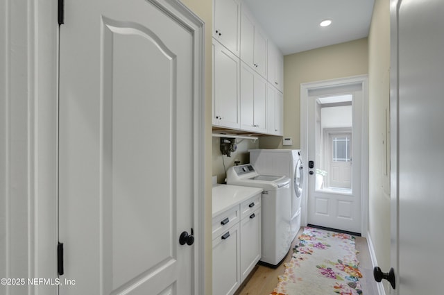 laundry area with light hardwood / wood-style floors, cabinets, and washer and clothes dryer