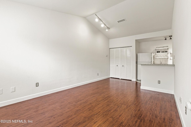 spare room featuring rail lighting, dark hardwood / wood-style flooring, and vaulted ceiling