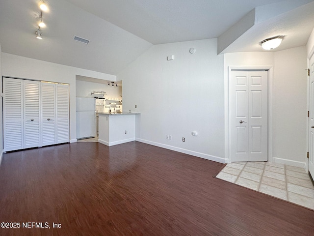 unfurnished living room featuring vaulted ceiling and dark wood-type flooring