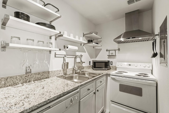 kitchen featuring wall chimney exhaust hood, white appliances, sink, and light stone counters