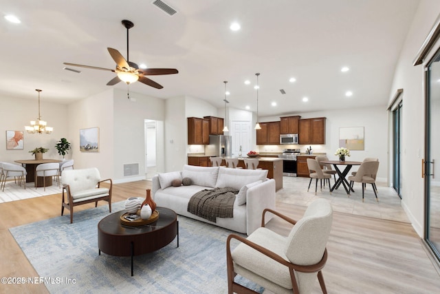 living room with light hardwood / wood-style floors and ceiling fan with notable chandelier