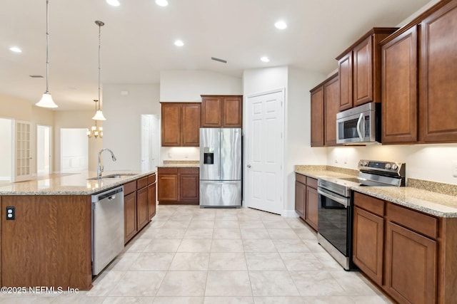 kitchen with decorative light fixtures, an island with sink, sink, and stainless steel appliances