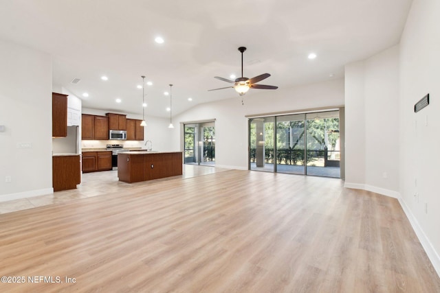 unfurnished living room with ceiling fan, light hardwood / wood-style floors, sink, and vaulted ceiling