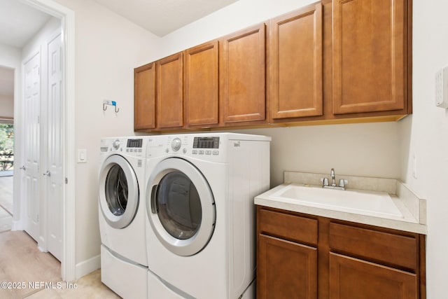 washroom with washing machine and dryer, cabinets, and sink