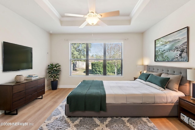 bedroom with ceiling fan, light hardwood / wood-style flooring, and a tray ceiling