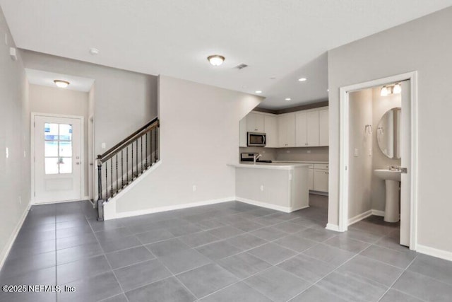 kitchen featuring white cabinets, tile patterned flooring, range, and kitchen peninsula