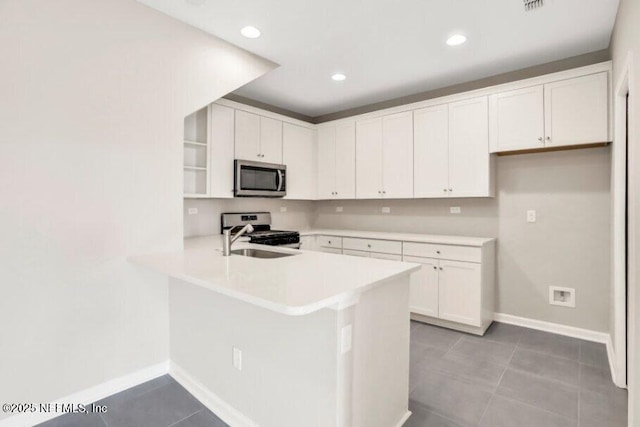 kitchen with stainless steel appliances, sink, white cabinets, kitchen peninsula, and tile patterned floors