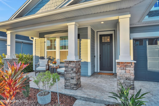 doorway to property featuring covered porch and a garage