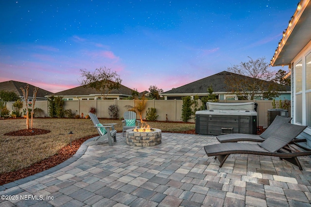 patio terrace at dusk featuring an outdoor fire pit and a hot tub