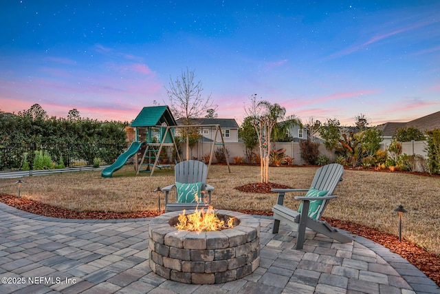 playground at dusk with a patio area and an outdoor fire pit