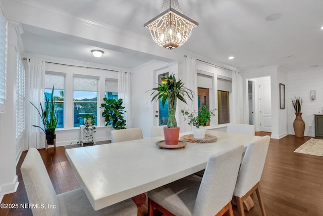 dining area featuring dark wood-type flooring, ornamental molding, and an inviting chandelier