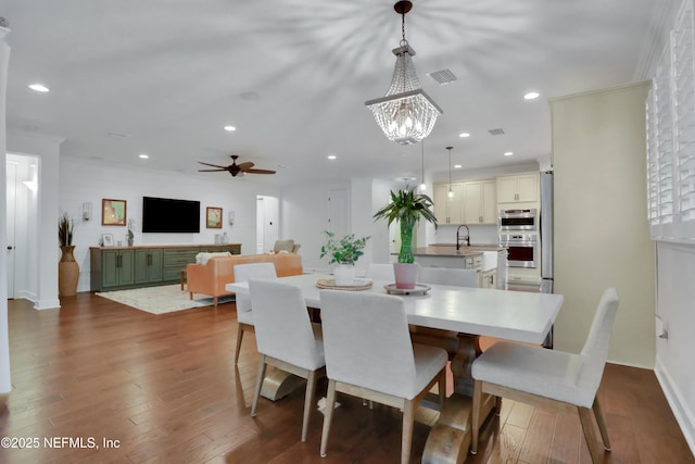 dining space featuring dark hardwood / wood-style floors, sink, and ceiling fan with notable chandelier