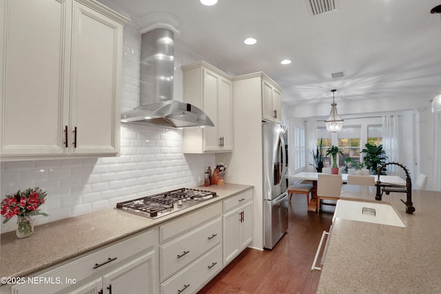 kitchen with stainless steel appliances, dark hardwood / wood-style floors, decorative light fixtures, wall chimney exhaust hood, and sink