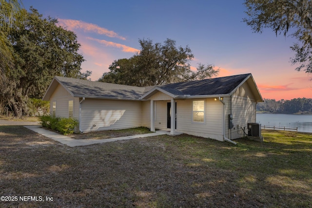 ranch-style home with a lawn, cooling unit, and a water view