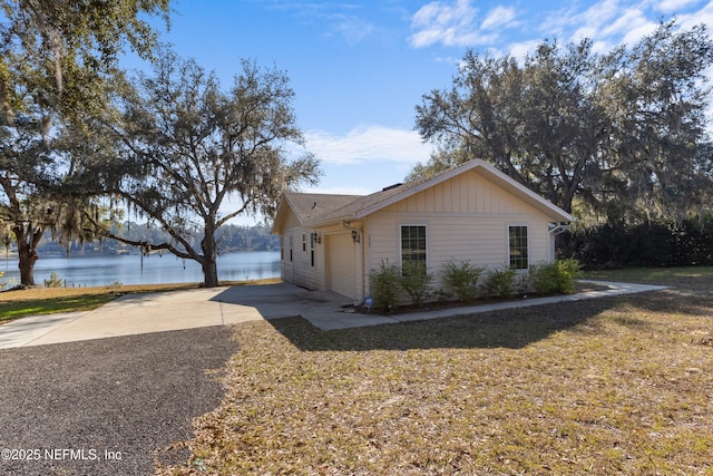 view of front of property featuring a front yard, a garage, and a water view