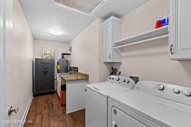 laundry area with cabinets, washing machine and dryer, dark wood-type flooring, water heater, and sink