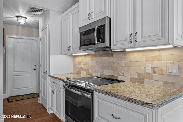 kitchen with light stone counters, white cabinets, appliances with stainless steel finishes, and dark hardwood / wood-style floors