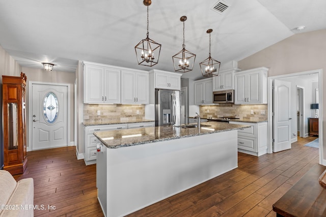 kitchen with appliances with stainless steel finishes, an island with sink, white cabinets, and sink