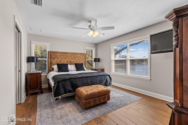 bedroom featuring multiple windows, a textured ceiling, ceiling fan, and hardwood / wood-style flooring