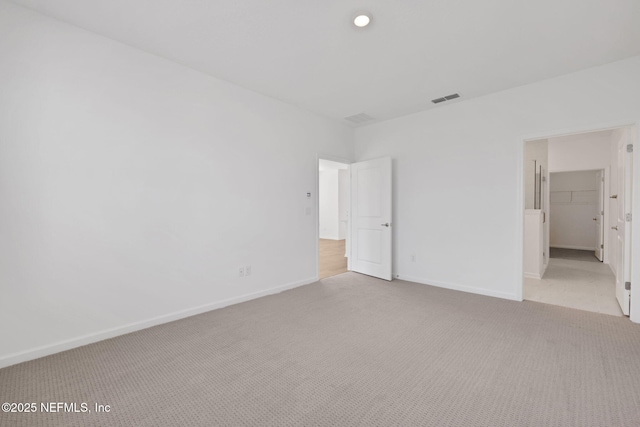 unfurnished bedroom with light carpet and a spacious closet