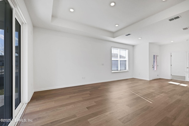 spare room featuring wood-type flooring and a tray ceiling