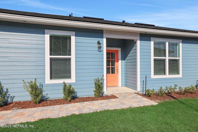 view of exterior entry featuring a lawn