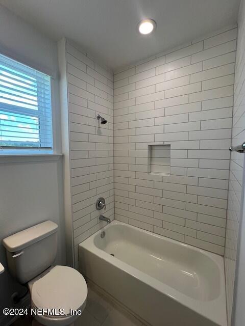 bathroom with toilet and tiled shower / bath