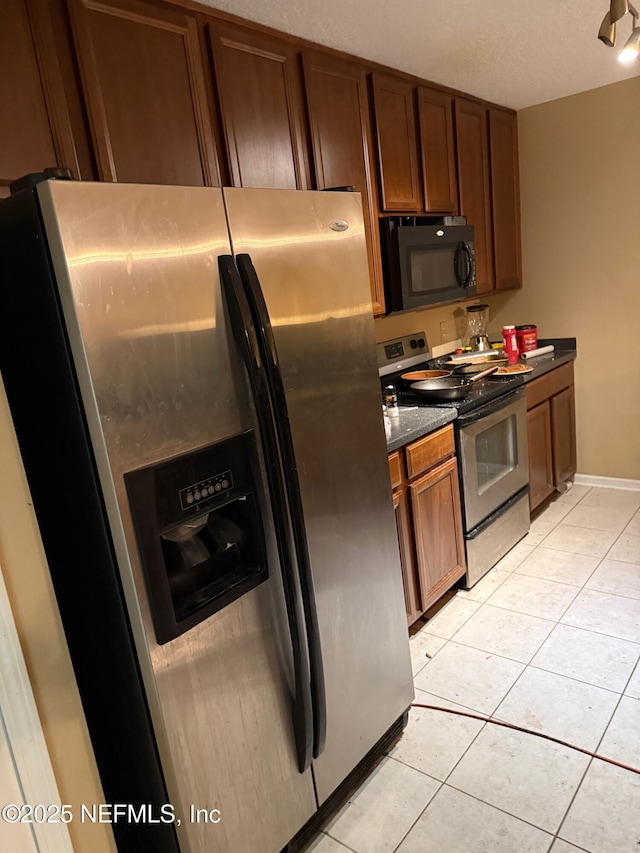 kitchen featuring dark stone countertops, appliances with stainless steel finishes, and light tile patterned flooring