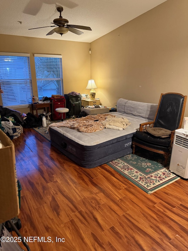 bedroom featuring a textured ceiling, ceiling fan, and dark hardwood / wood-style flooring