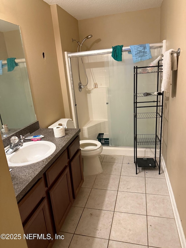 bathroom featuring toilet, vanity, tile patterned floors, a textured ceiling, and a shower with door