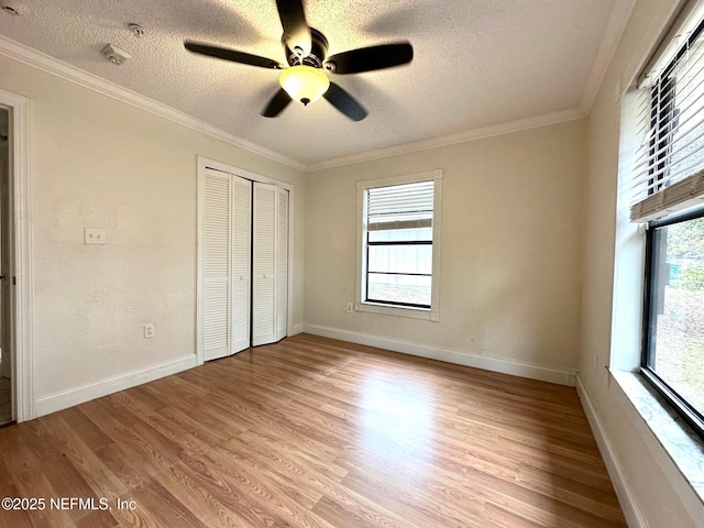 unfurnished bedroom with ceiling fan, ornamental molding, a closet, and multiple windows