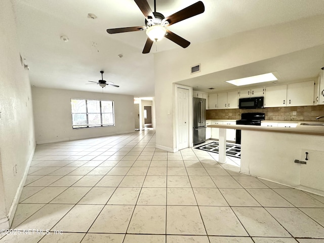 kitchen with black appliances, decorative backsplash, sink, light tile patterned floors, and white cabinets