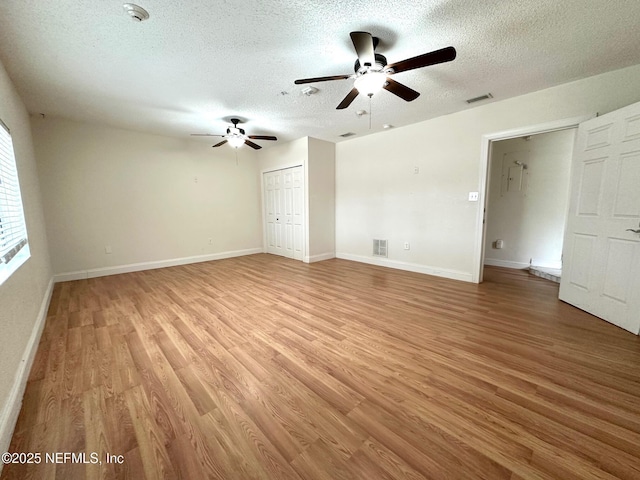 interior space with ceiling fan, a textured ceiling, and light hardwood / wood-style flooring