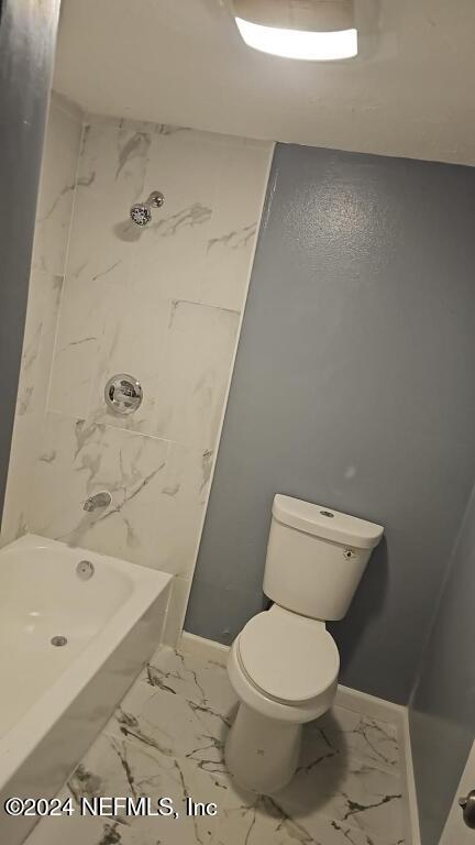 bathroom featuring tiled shower / bath and toilet