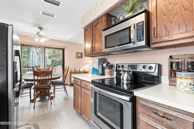 kitchen with a textured ceiling, light tile patterned floors, appliances with stainless steel finishes, and ceiling fan