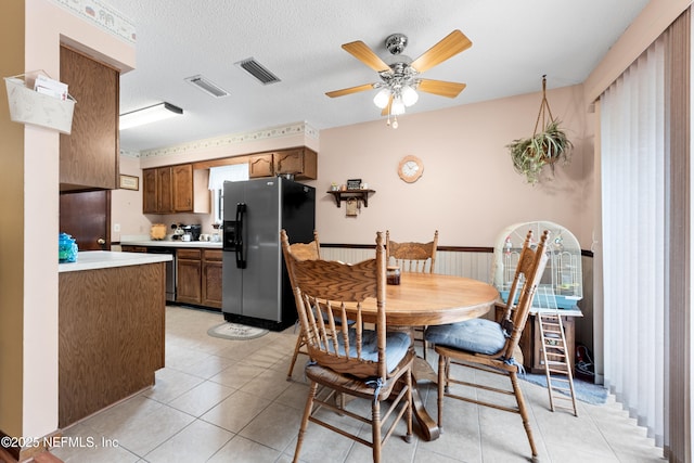 tiled dining area featuring ceiling fan and a textured ceiling