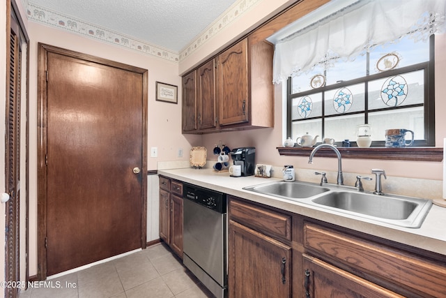 kitchen featuring dishwasher, sink, a textured ceiling, light tile patterned floors, and dark brown cabinets