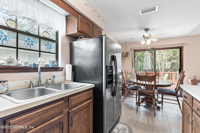 kitchen with a textured ceiling, sink, stainless steel fridge with ice dispenser, ceiling fan, and light tile patterned floors