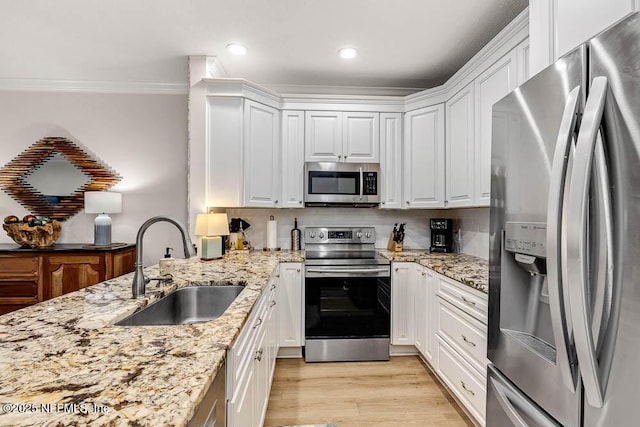 kitchen with stainless steel appliances, light stone countertops, sink, white cabinets, and crown molding