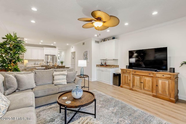 living room featuring light wood-type flooring, crown molding, and ceiling fan