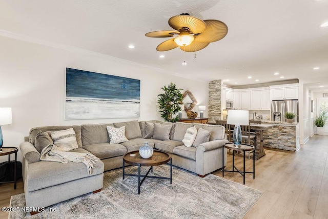 living room with crown molding, ceiling fan, and light hardwood / wood-style flooring