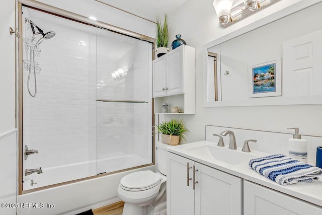 full bathroom featuring bath / shower combo with glass door, vanity, and toilet