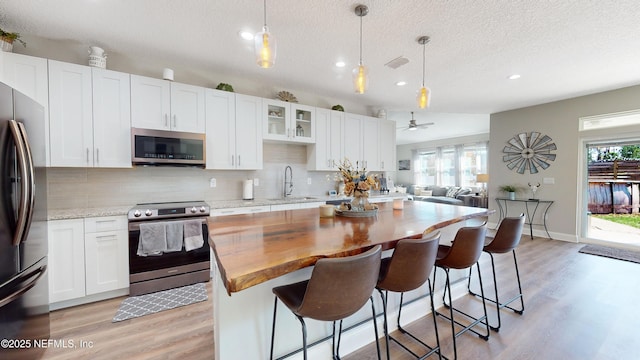 kitchen featuring a textured ceiling, appliances with stainless steel finishes, white cabinetry, and sink