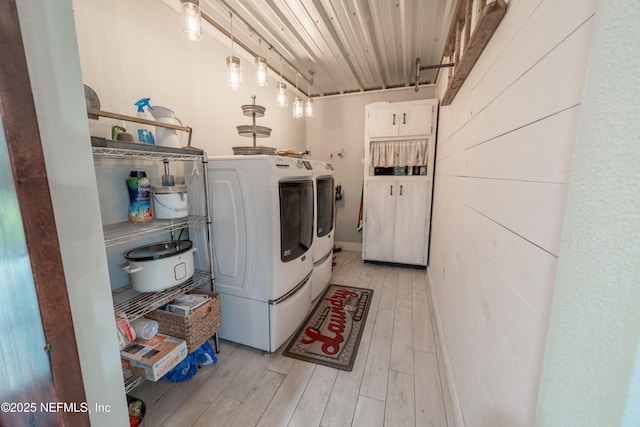 laundry room with light wood-type flooring and washing machine and clothes dryer