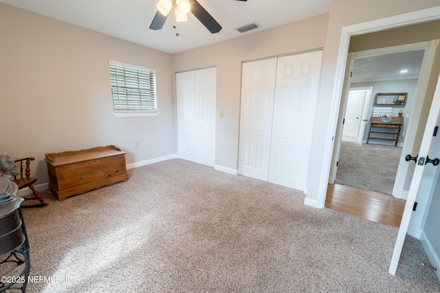 carpeted bedroom with ceiling fan and two closets